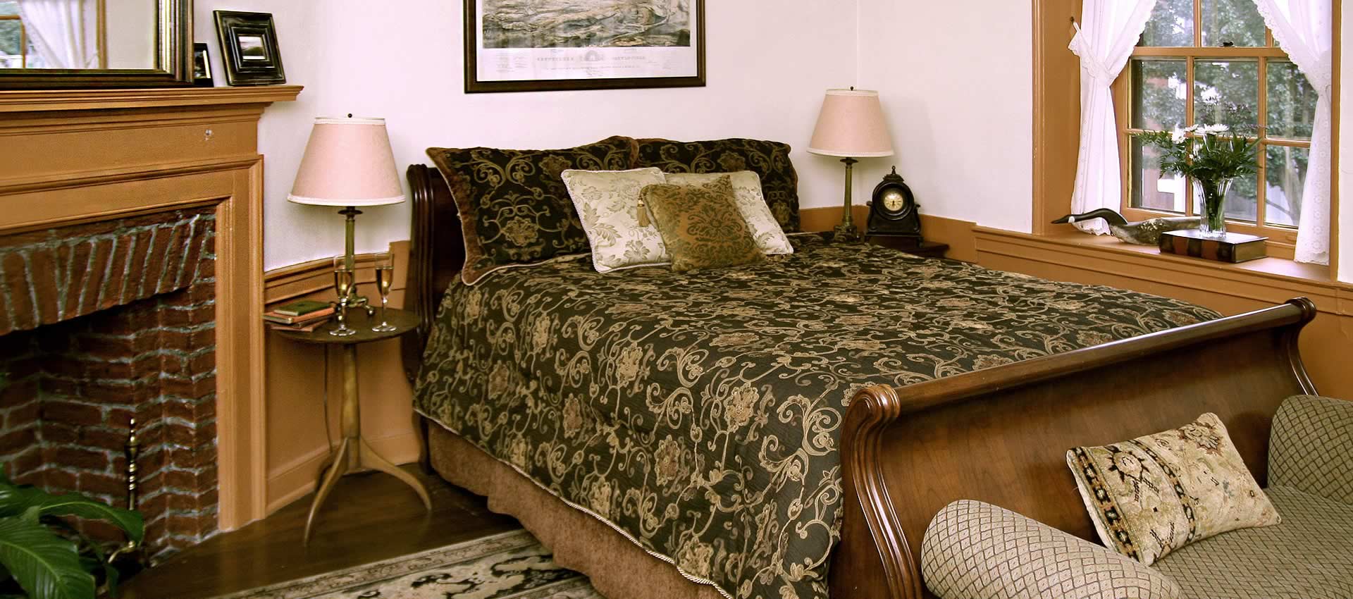 The bed of the Battle room with fireplace mantle with the musket ball hole